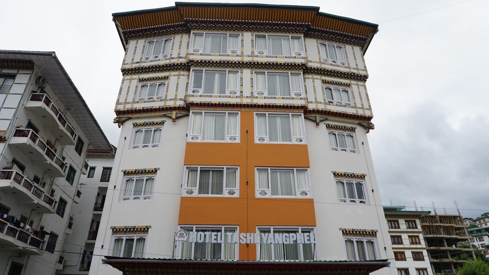 The hotel from the street: a tall building rendered in orange and white, with traditional Bhutanese painted window surrounds